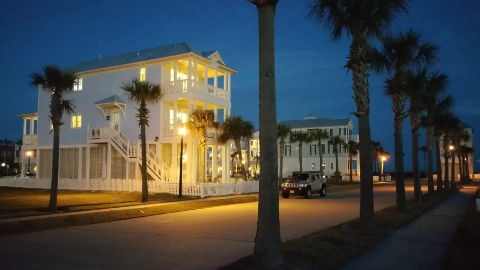 SeaGlass at Beachtown, lit up beneath palm trees at dusk